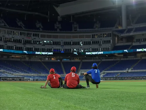 Three people sitting on the ground in an empty sports stadium