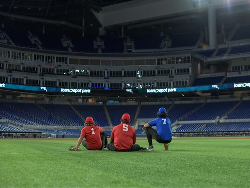 Three people sitting on the ground in an empty sports stadium