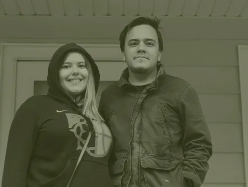 A couple standing in their porch, smiling