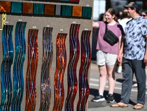 Visitors at an art fair with glass art in the foreground