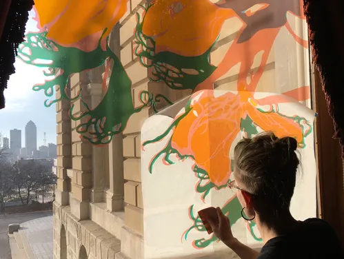 Artist applying transfer of their floral artwork to a window