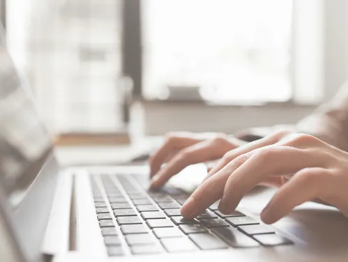 Fingers typing on laptop keyboard