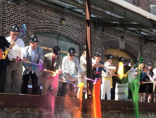 People in hard hats dumping shovels of colored powder onto the ground 