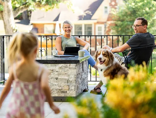 A family sits outside on their patio with a dog