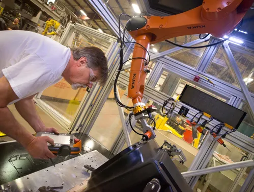 Man working in a factory with a robotic arm