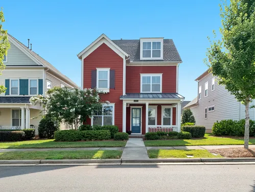 Exterior of a red multi-story home in a neighborhood