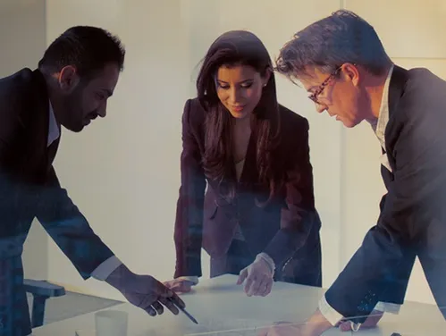 Businesspeople standing around a table examining a document