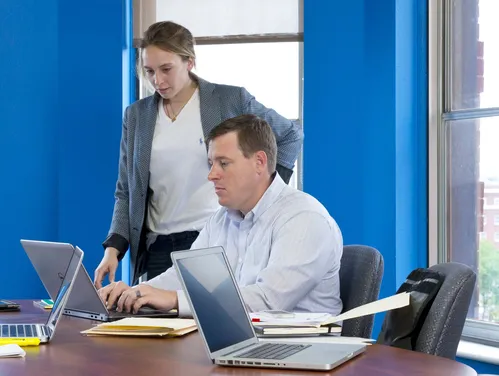 People with laptops in front of blue walls