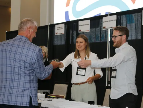 Two people help and event attendee check in at registration