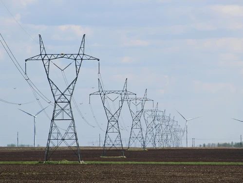 Transmission towers and wind turbines on a field