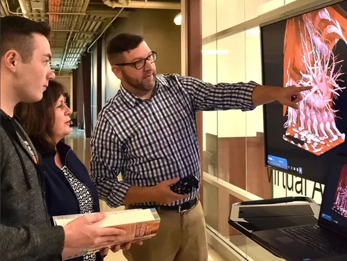People in front of a hi-tech screen while one of them is pointing at a detail