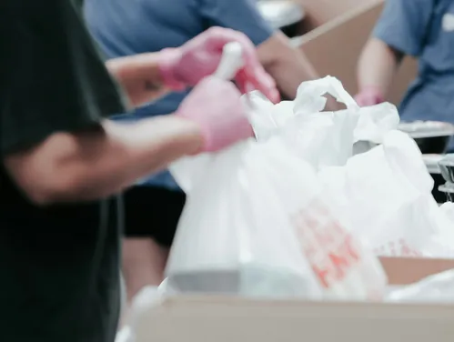 Hands bagging food from cardboard boxes