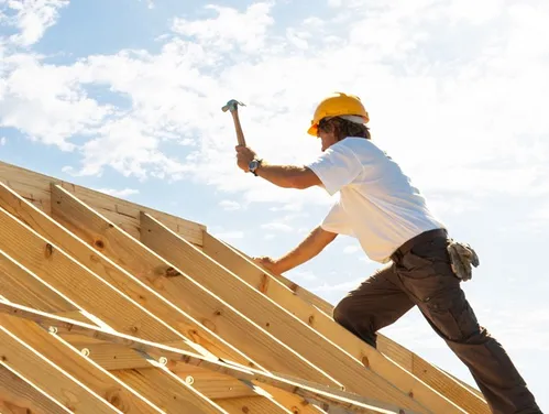 Construction worker hammering on the roof of a house being built