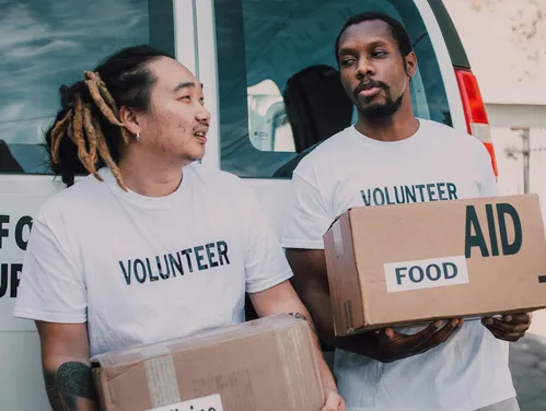 Two people in Volunteer shirts with boxes of food aid