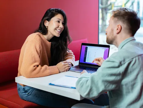Man and woman talking and looking at laptop