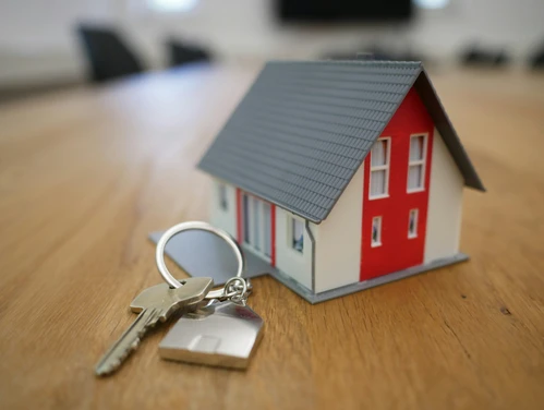 Red and white miniature house and set of keys on table