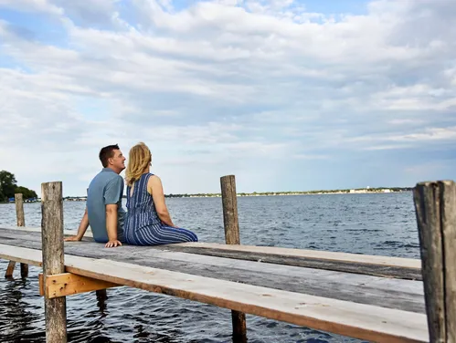 Man and woman sitting on dock looking out at a lake