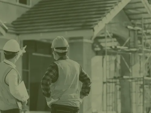 Two construction workers looking at house
