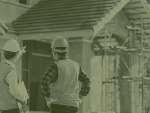 Two construction workers looking at house