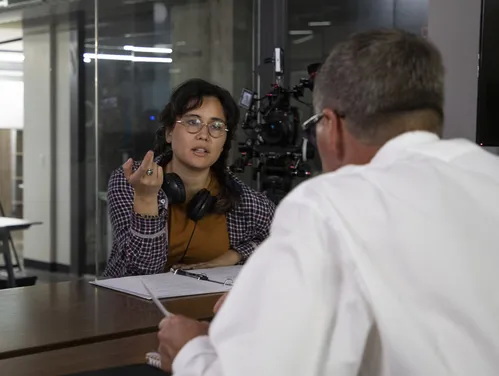 Person wearing headphones having a conversation with another person with a binder in front of them