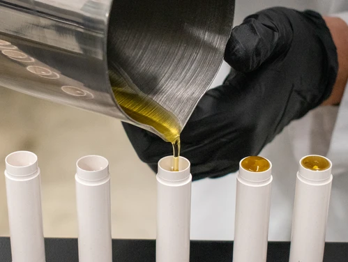 Gloved hands filling lip balm containers