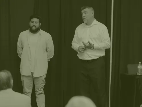 Two businessmen talking in front of an audience