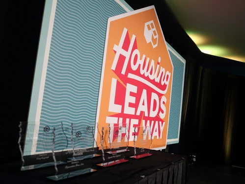 Trophies in front of Housing Leads the Way sign