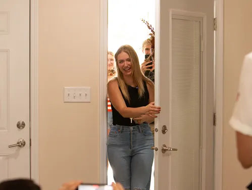 woman smiling while opening the front door of a home