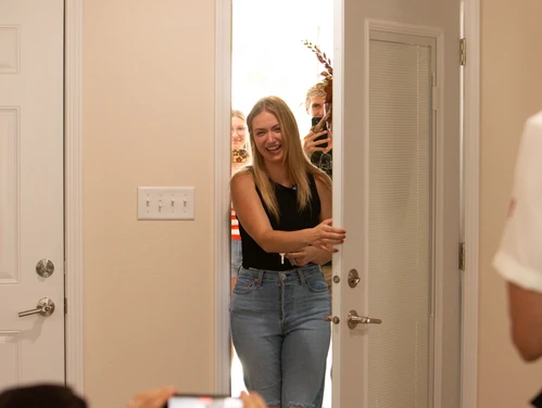 woman smiling while opening the front door of a home