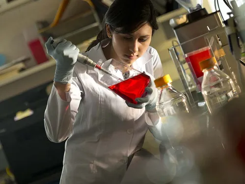 Scientist working with a vial of red liquid in a lab