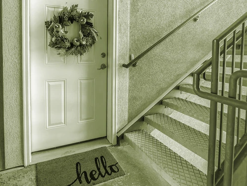 Apartment door with wreath and mat next to step
