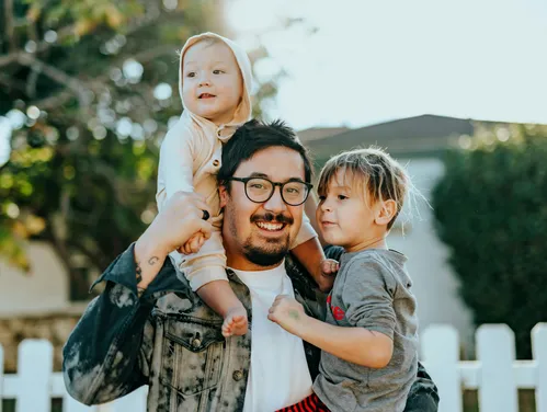 Man in white shirt holding baby and toddler