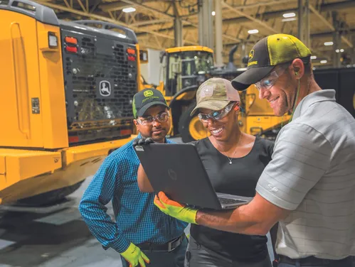 Workers in the John Deere factory looking at a laptop