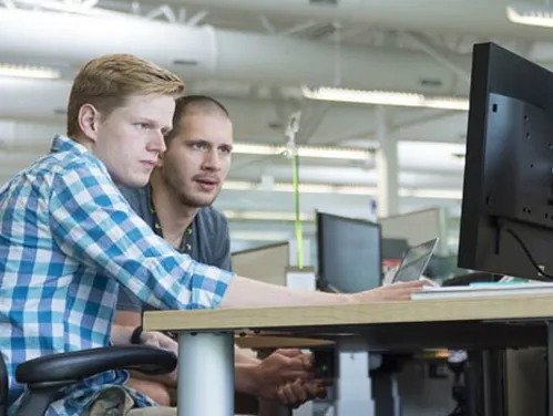 two people looking at a desktop computer