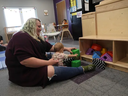 Women in a daycare setting playing with a baby