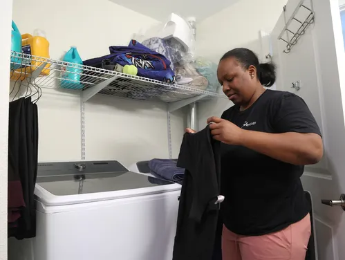 Woman holding up a shirt while doing laundry