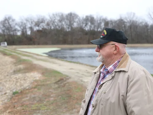 Moravia's mayor, wearing a baseball cap, stands in front of the city lagoon