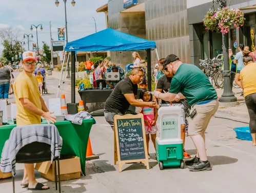 people gathered at a street event with tents and vendors