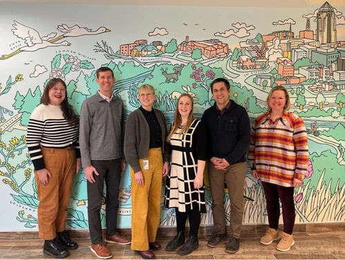 six people standing in front of a mural