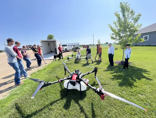 Drone team standing with a large drone on a lawn