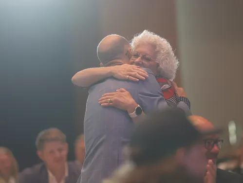 two people hugging at an awards ceremony