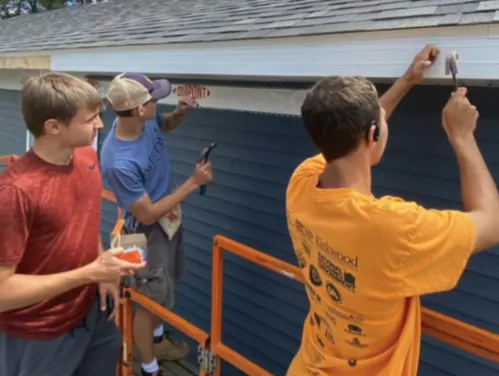 three people working on the exterior of a house