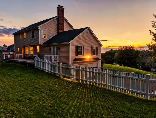 single family home with a large yard and fence at sunset
