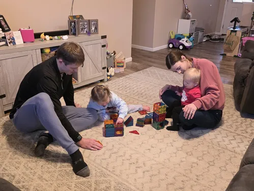 Mom and Dad stacking blocks with two children.