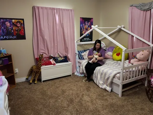 Mom feeding baby with a bottle on a bed.