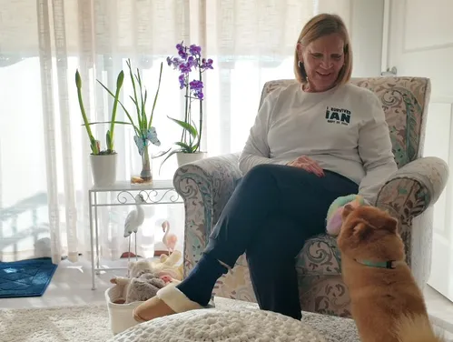 Woman sitting on couch with dog below.