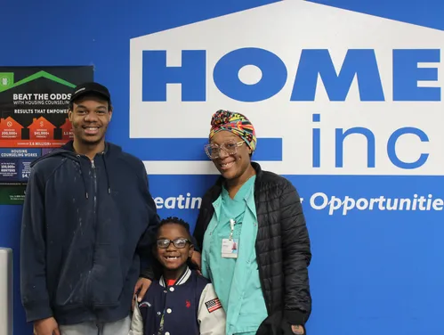 Family standing in front of HOME Inc. wall