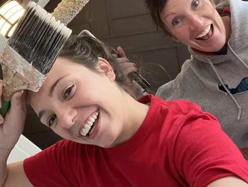 Two women with paintbrush held up.