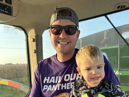 Father and son riding on tractor.