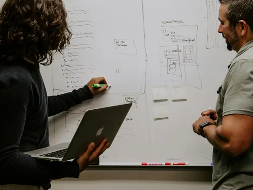 two people working with a laptop and whiteboard